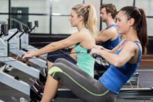 Trois personnes pratiquant le rameur dans une salle de sport